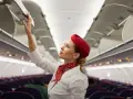 Flugbegleiterin schließt Gepäckfach. Ein Beruf, der mehr als nur das Flugbegleiter Gehalt bietet.