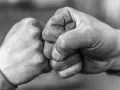 Zwei Fäuste stoßen zusammen, ein Zeichen von Solidarität und Verbundenheit.