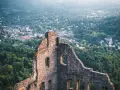 Ruinen einer Burg mit Blick auf eine Stadt und bewaldete Hügel.