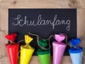 Bunte Schultüten vor einer Tafel mit "Schulanfang" für die Einschulung Hessen 2025.