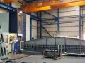 Ein junger Zerspanungsmechaniker in blauer Latzhose steht vor einer großen Soraluce-Maschine in einer Werkshalle. Daneben liegen massive Metallteile.