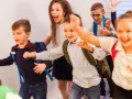 Fröhliche Schulkinder mit Rucksäcken rennen los.