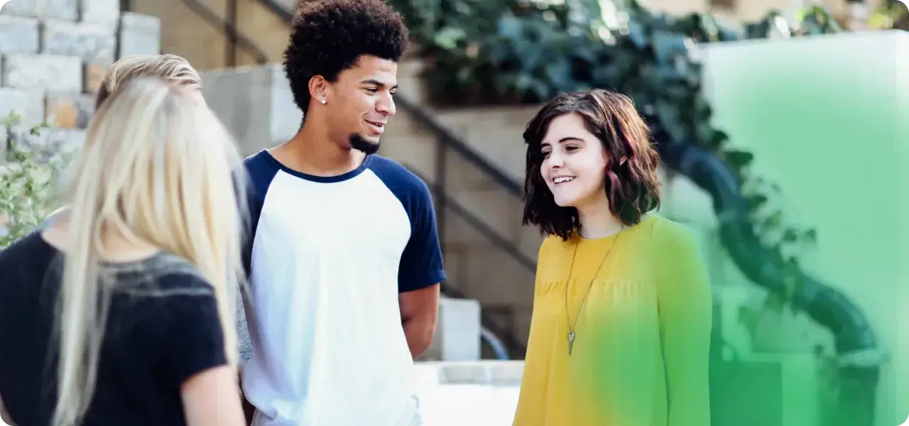Eine Gruppe junger Leute, der gen z jahrgang, lacht und unterhält sich im Freien.