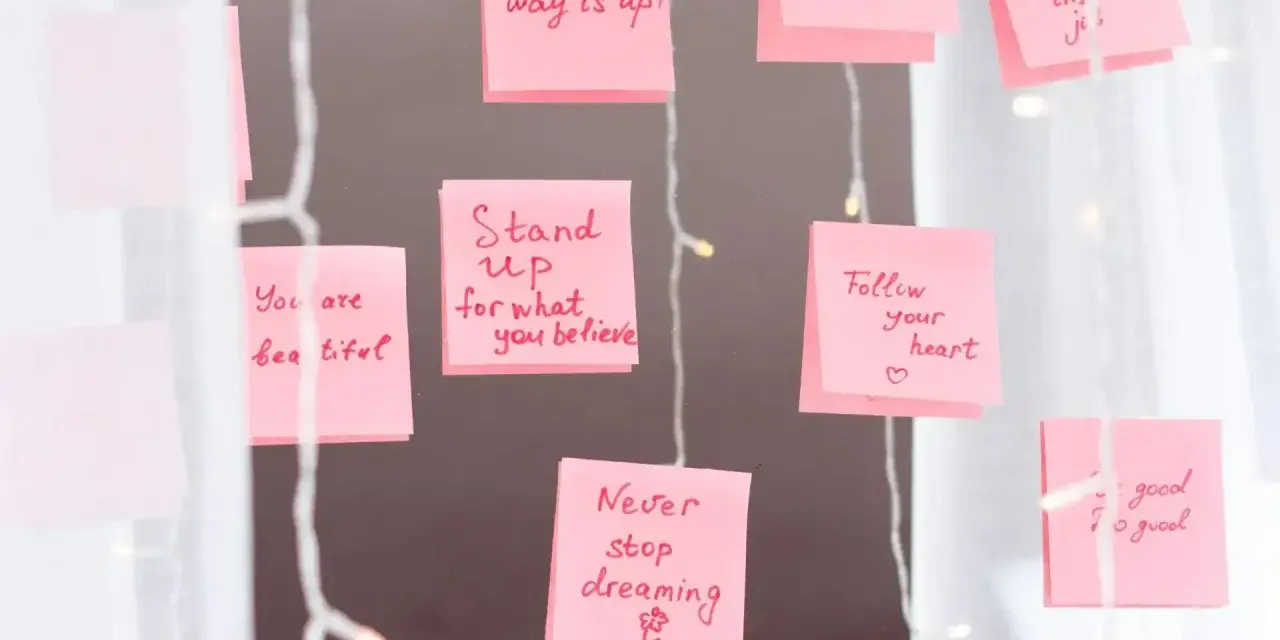 Rosa Haftnotizen mit inspirierenden Affirmationen wie "Think BIG" und "Never stop dreaming" hängen an einer Lichterkette.