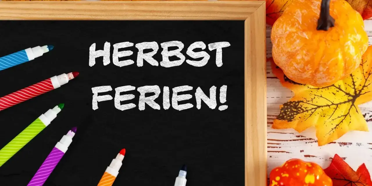Bunte Stifte und Herbstdeko umrahmen eine Tafel mit der Aufschrift "Herbstferien!". Zeit für die Herbstferien Baden-Württemberg 2025!