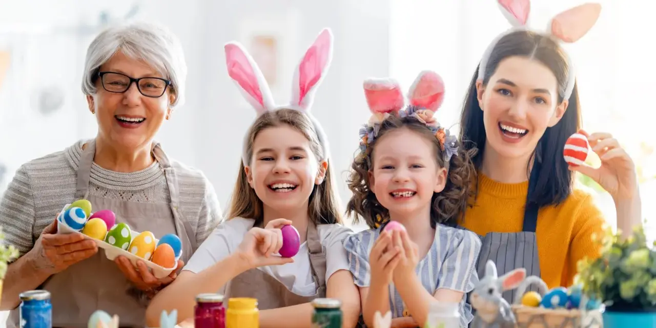 Familie feiert die Osterferien BW 2026 mit bunten Eiern und Hasenohren.