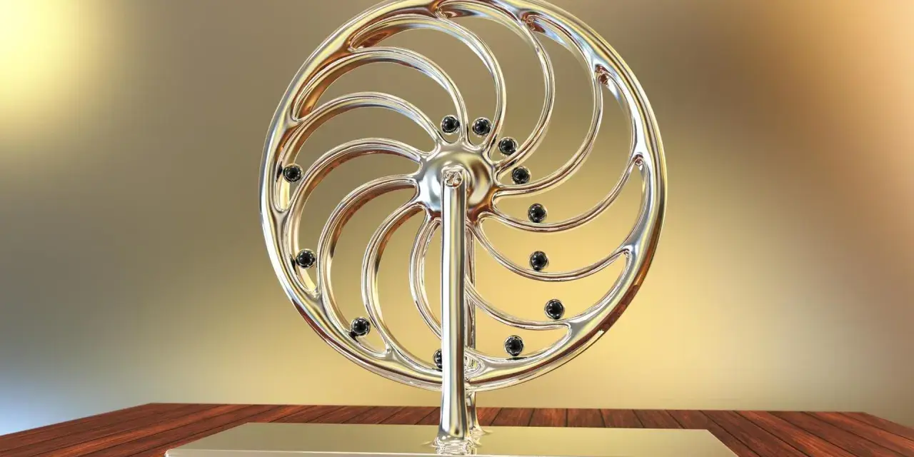 Glänzendes Rad mit schwarzen Kugeln, das an ein Perpetuum mobile erinnert, steht auf einem Holztisch.