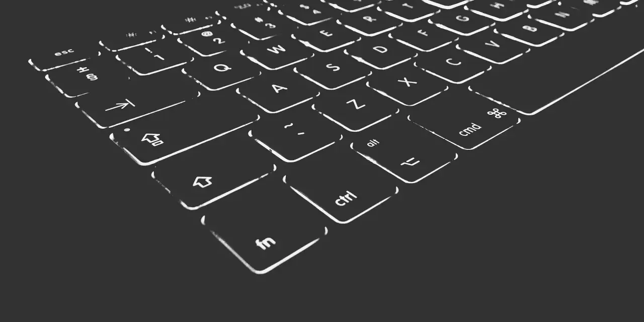 Nahaufnahme einer beleuchteten Tastatur. Die Tasten sind mit weißen Symbolen und Buchstaben versehen, die im Dunkeln leuchten. Die "Umschalt"-Taste ist deutlich zu erkennen.