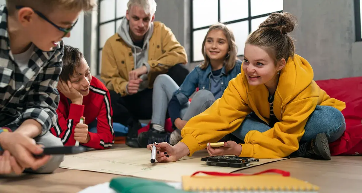 Kinder und Jugendliche arbeiten begeistert an einem Projekt. Der **Präsenzunterricht** fördert Kreativität und Teamwork.