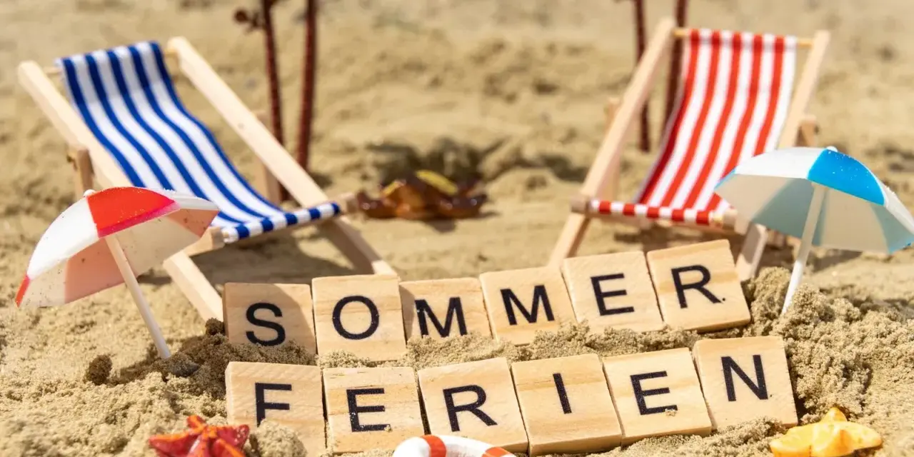 Strandkörbchen, Palmen und die Worte "Sommerferien" im Sand. Berlin wartet auf die Sommerferien 2026!
