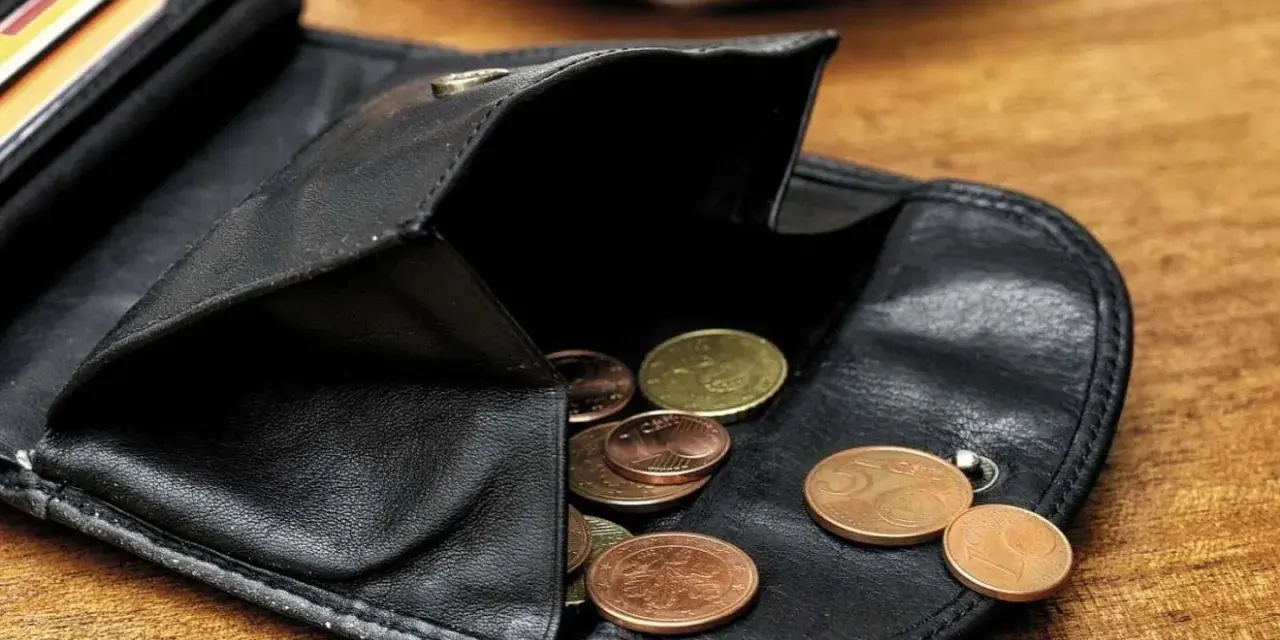 Schwarzes Lederportemonnaie mit Münzen. Die wenigen Münzen symbolisieren die Opportunitätskosten, wenn man sich für eine Ausgabe entscheidet.