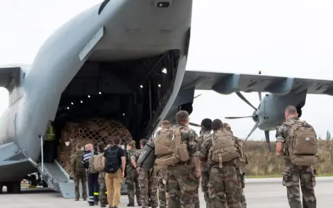 Soldaten mit Rucksäcken stehen vor einem Frachtflugzeug, bereit für ihren Einsatz im Afghanistan-Krieg.