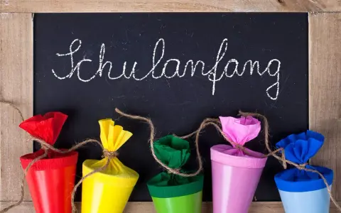 Bunte Schultüten vor einer Tafel mit "Schulanfang" für die Einschulung Hessen 2025.