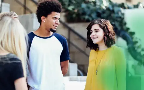 Eine Gruppe junger Leute, der gen z jahrgang, lacht und unterhält sich im Freien.
