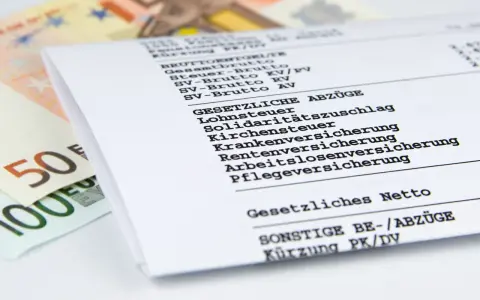 Nahaufnahme einer Entgeltabrechnung mit Euro-Scheinen. Die Abrechnung zeigt Brutto- und Nettobeträge sowie gesetzliche Abzüge wie Lohnsteuer und Versicherungen.