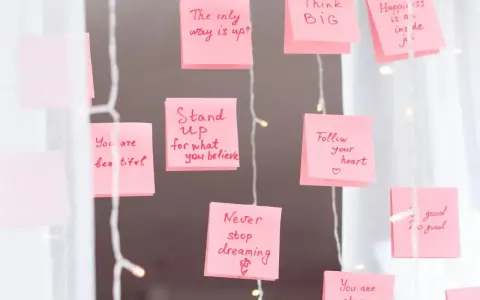 Rosa Haftnotizen mit inspirierenden Affirmationen wie "Think BIG" und "Never stop dreaming" hängen an einer Lichterkette.