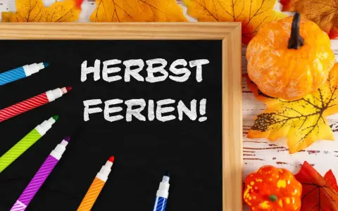 Bunte Stifte und Herbstdeko umrahmen eine Tafel mit der Aufschrift "Herbstferien!". Zeit für die Herbstferien Baden-Württemberg 2025!