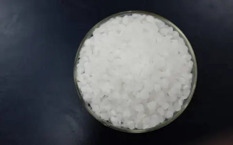 Schale mit weißen Pellets, die Natriumhydroxid darstellen.