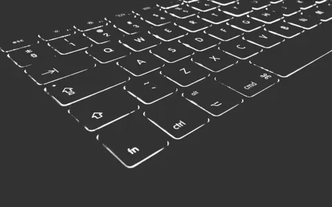 Nahaufnahme einer beleuchteten Tastatur. Die Tasten sind mit weißen Symbolen und Buchstaben versehen, die im Dunkeln leuchten. Die "Umschalt"-Taste ist deutlich zu erkennen.