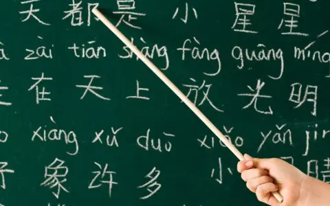 Kreide auf Tafel: Chinesische Schriftzeichen und Pinyin. Manche sagen, Chinesisch sei die schwerste Sprache der Welt.