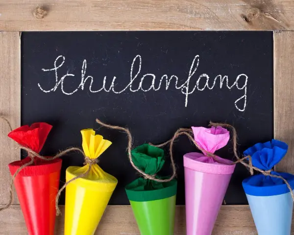 Bunte Schultüten vor einer Tafel mit "Schulanfang" für die Einschulung Hessen 2025.