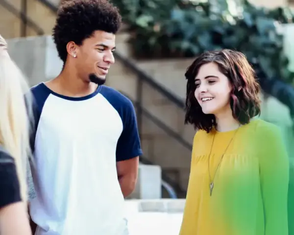 Eine Gruppe junger Leute, der gen z jahrgang, lacht und unterhält sich im Freien.