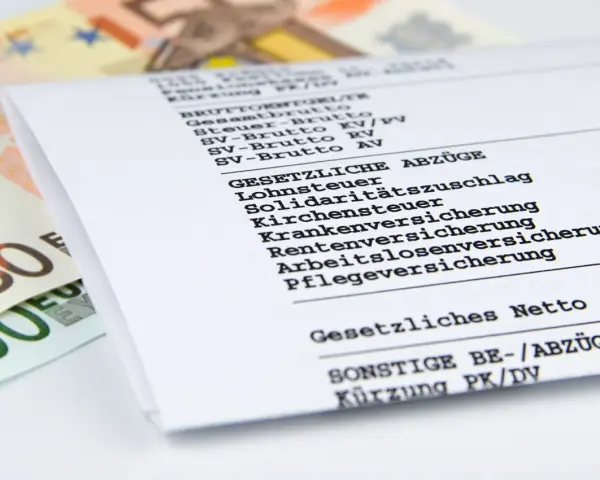 Nahaufnahme einer Entgeltabrechnung mit Euro-Scheinen. Die Abrechnung zeigt Brutto- und Nettobeträge sowie gesetzliche Abzüge wie Lohnsteuer und Versicherungen.
