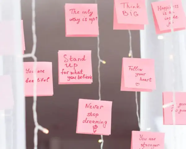 Rosa Haftnotizen mit inspirierenden Affirmationen wie "Think BIG" und "Never stop dreaming" hängen an einer Lichterkette.