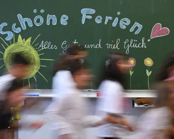 Schöne Ferien! Kinder freuen sich auf die Osterferien 2026 in NRW. Die Tafel zeigt Sonne, Blumen und ein Herz.