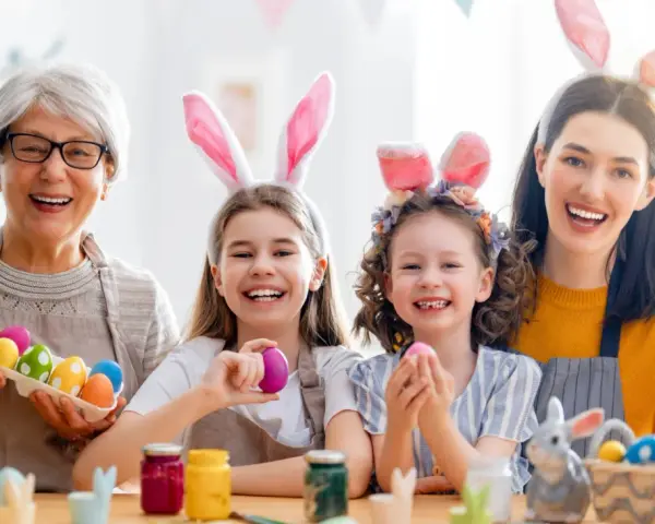 Familie feiert die Osterferien BW 2026 mit bunten Eiern und Hasenohren.