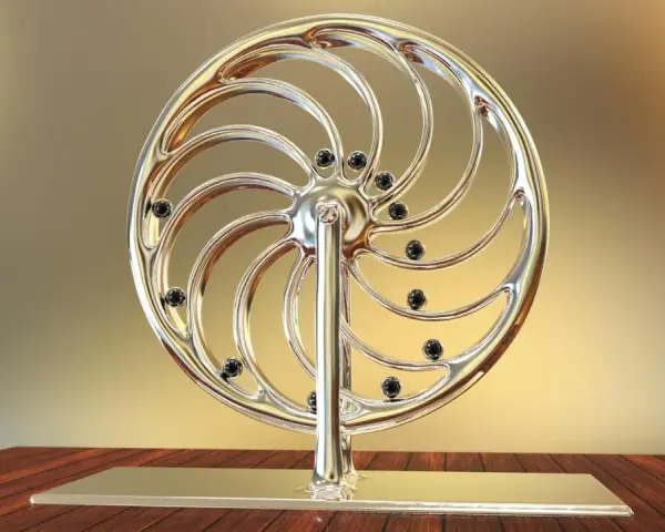 Glänzendes Rad mit schwarzen Kugeln, das an ein Perpetuum mobile erinnert, steht auf einem Holztisch.