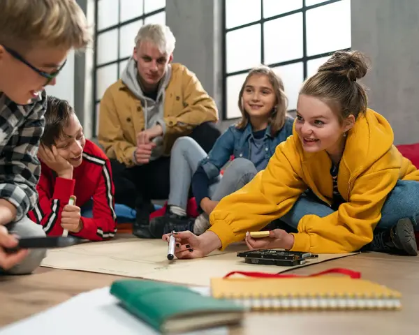 Kinder und Jugendliche arbeiten begeistert an einem Projekt. Der **Präsenzunterricht** fördert Kreativität und Teamwork.
