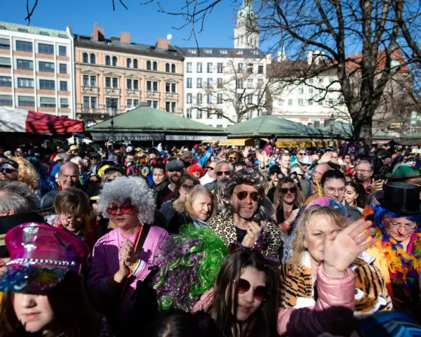 Bunte Kostüme und fröhliche Gesichter beim Fasching in Bayern 2027. Eine ausgelassene Menge feiert ausgelassen.
