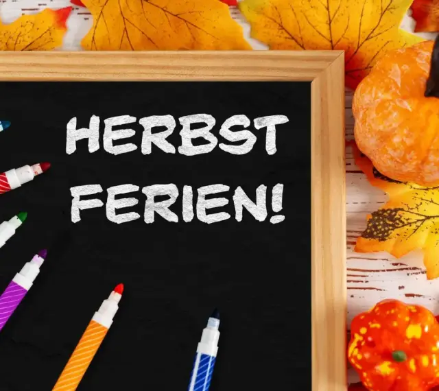 Bunte Stifte und Herbstdeko umrahmen eine Tafel mit der Aufschrift "Herbstferien!". Zeit für die Herbstferien Baden-Württemberg 2025!