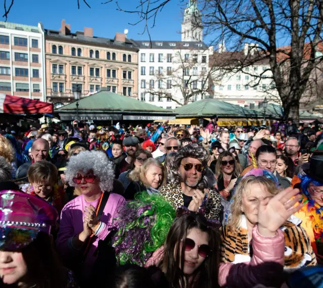 Bunte Kostüme und fröhliche Gesichter beim Fasching in Bayern 2027. Eine ausgelassene Menge feiert ausgelassen.