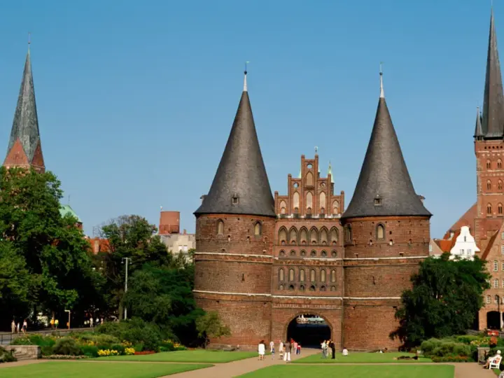 Holstentor in Lübeck, ein Wahrzeichen für Ihre **Ferien Schleswig-Holstein 2025**. Historische Backsteinarchitektur mit Türmen und grünen Parks.