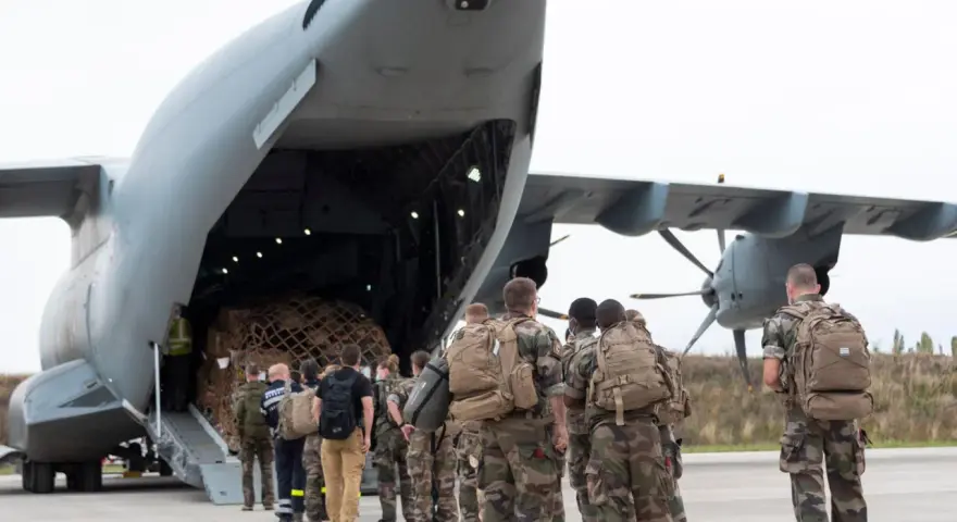 Soldaten mit Rucksäcken stehen vor einem Frachtflugzeug, bereit für ihren Einsatz im Afghanistan-Krieg.