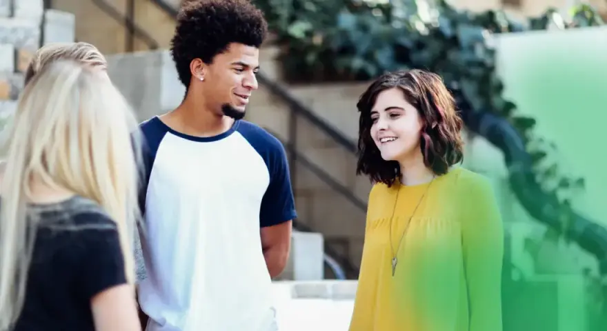 Eine Gruppe junger Leute, der gen z jahrgang, lacht und unterhält sich im Freien.