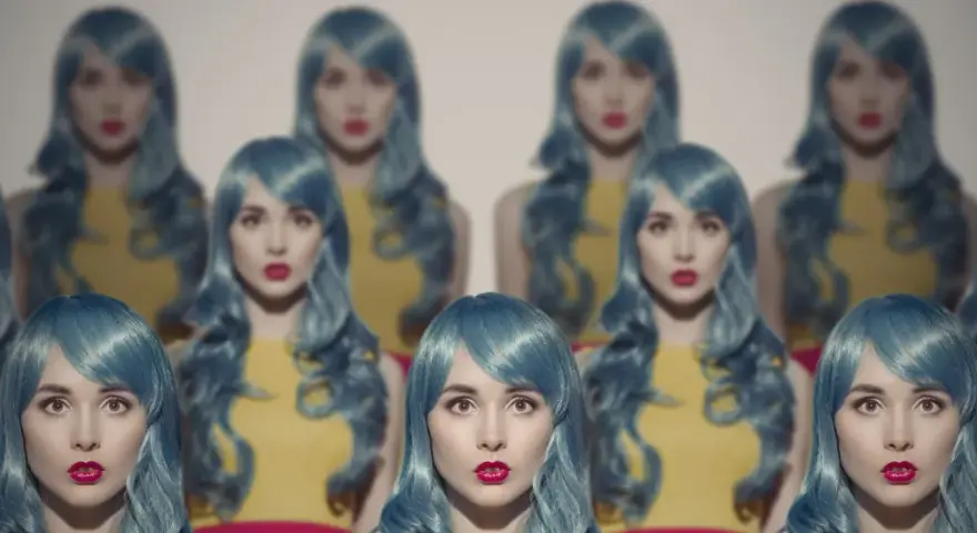 Mehrere Frauen mit blauen Perücken und roten Lippen scheinen sich zu klonen, eine surreale Szene.