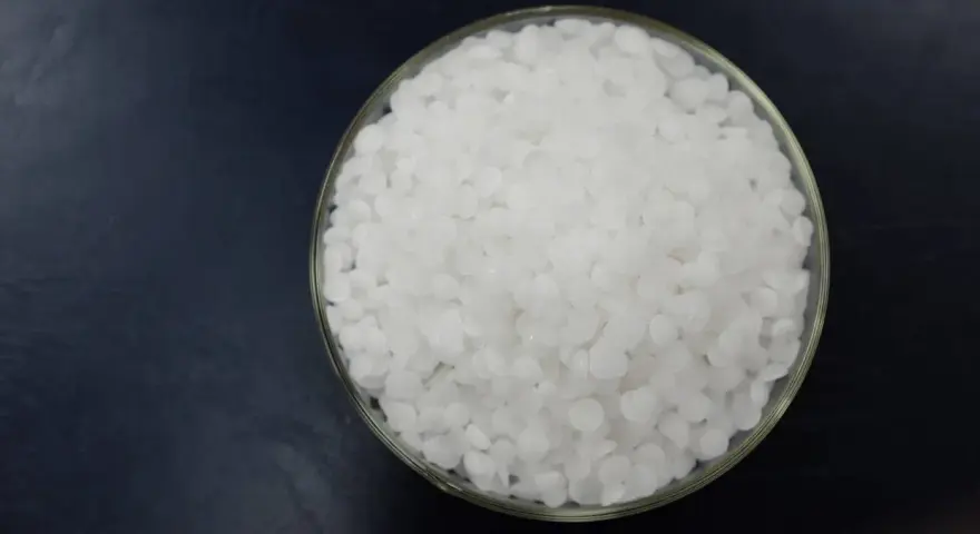 Schale mit weißen Pellets, die Natriumhydroxid darstellen.