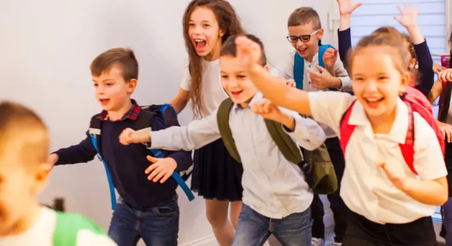 Fröhliche Schulkinder mit Rucksäcken rennen los.