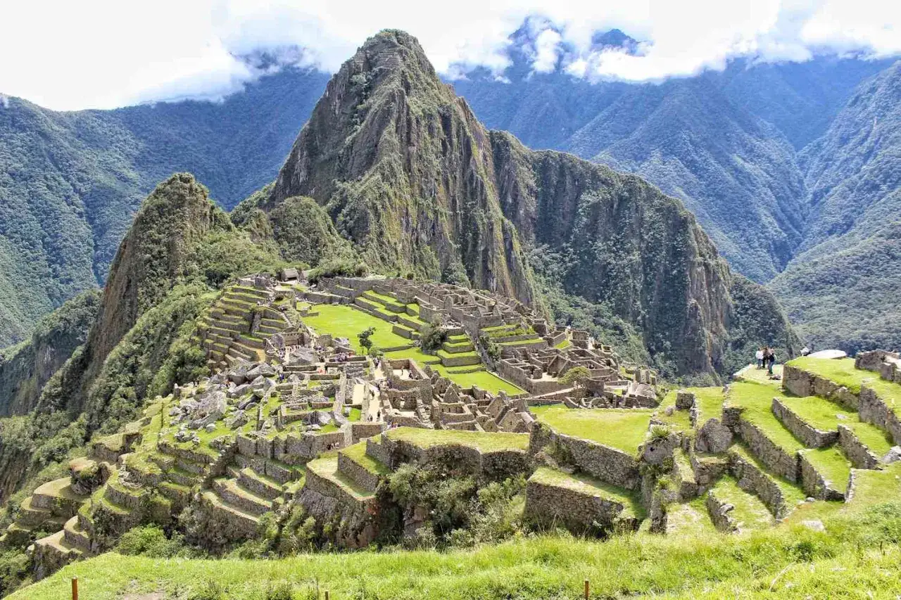 Machu Picchu, eines der 7 Weltwunder, thront majestätisch in den Anden. Terrassen und Ruinen erstrecken sich über den grünen Berg.