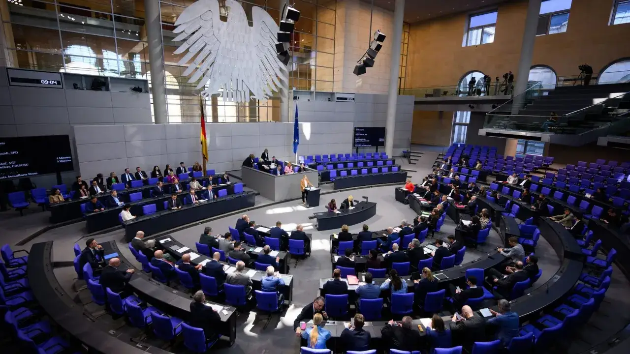 Bundestagsdebatte im Plenarsaal. Die Abgeordneten diskutieren, während die Uhr 09:04 anzeigt. Das Thema könnte das bundestagsabgeordnete gehalt sein.