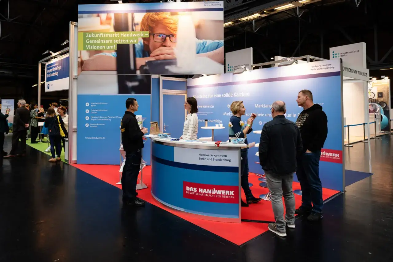 Messe-Stand für Employer Branding: Handwerkskammern werben für Karrieren im Handwerk. Menschen im Gespräch, Infomaterial und ein großes Banner mit Visionen.