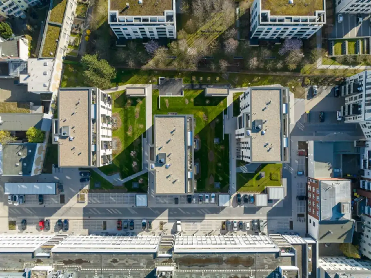 Moderne Wohnanlage im Vorort mit begrünten Dächern, gepflegten Grünflächen und Parkplätzen.
