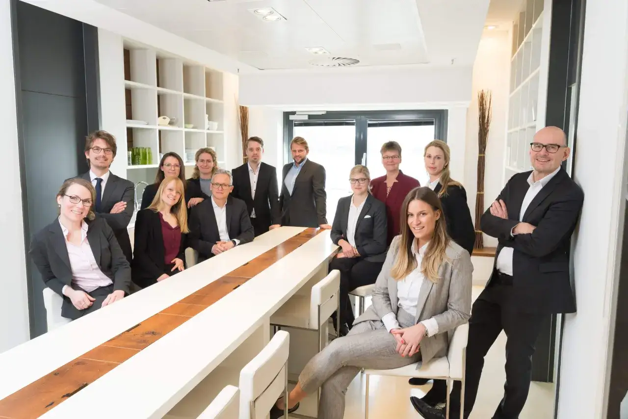 Ein Team von Beratern in einem modernen Büro, das sich um einen langen Tisch versammelt.