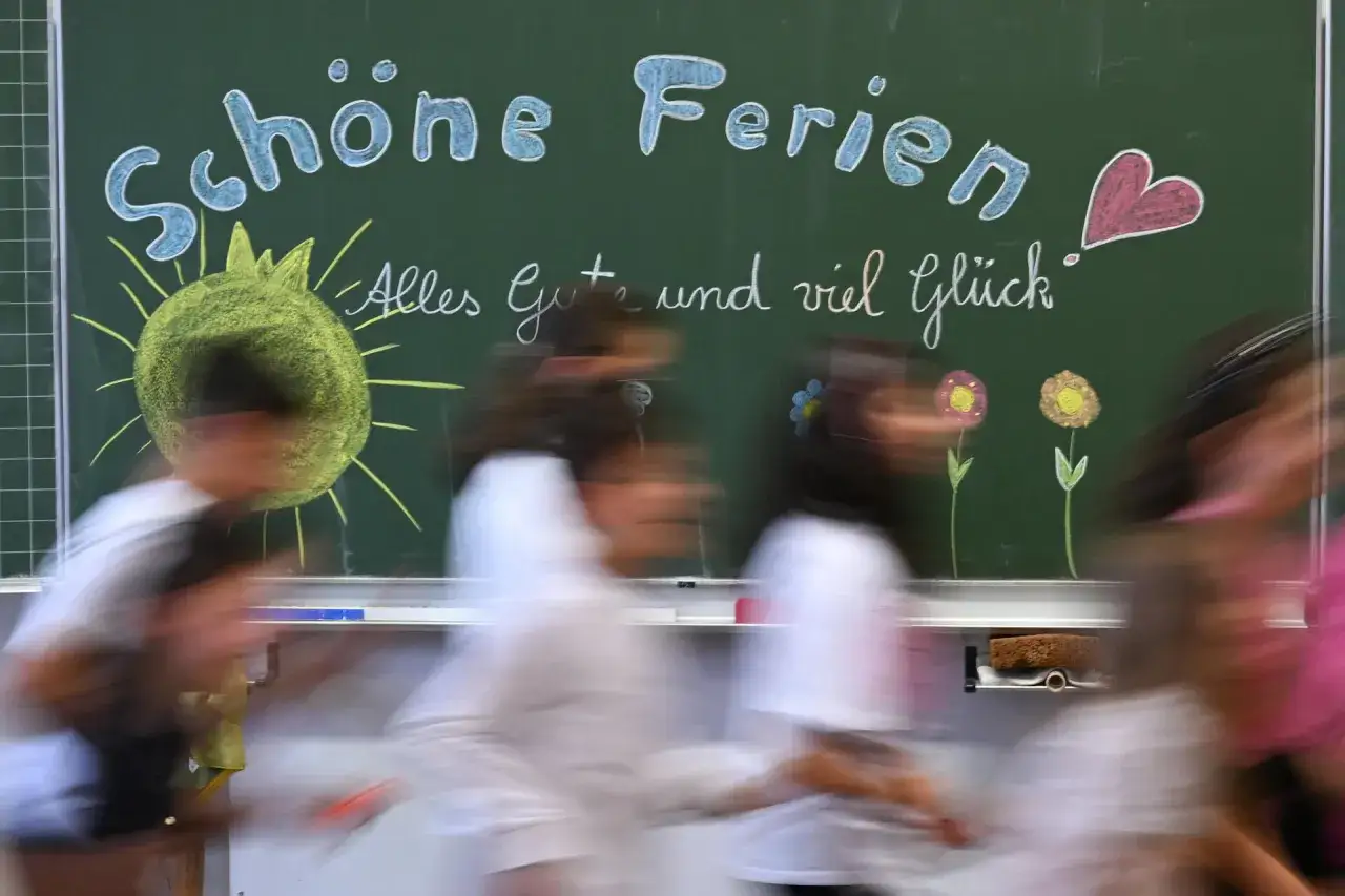 Schöne Ferien! Kinder freuen sich auf die Herbstferien 2025 NRW. Kreidezeichnungen von Sonne, Herz und Blumen auf der Tafel.