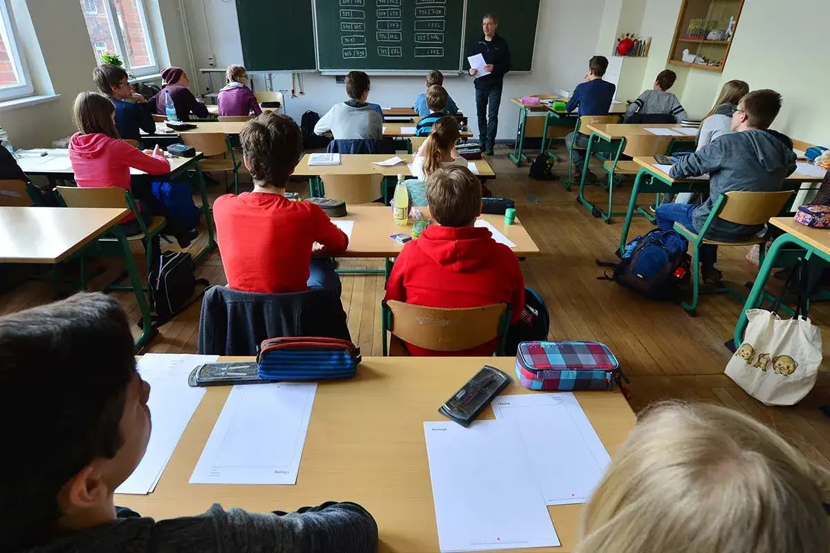 Schüler im Präsenzunterricht, konzentriert auf den Lehrer an der Tafel.