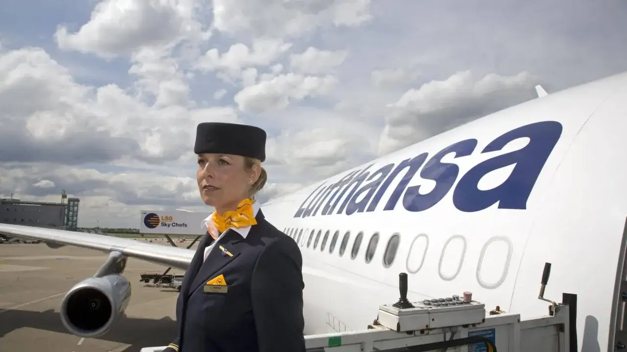Flugbegleiterin in Uniform vor Lufthansa-Flugzeug. Das Gehalt eines Flugbegleiters ist ein wichtiger Faktor für die Berufswahl.