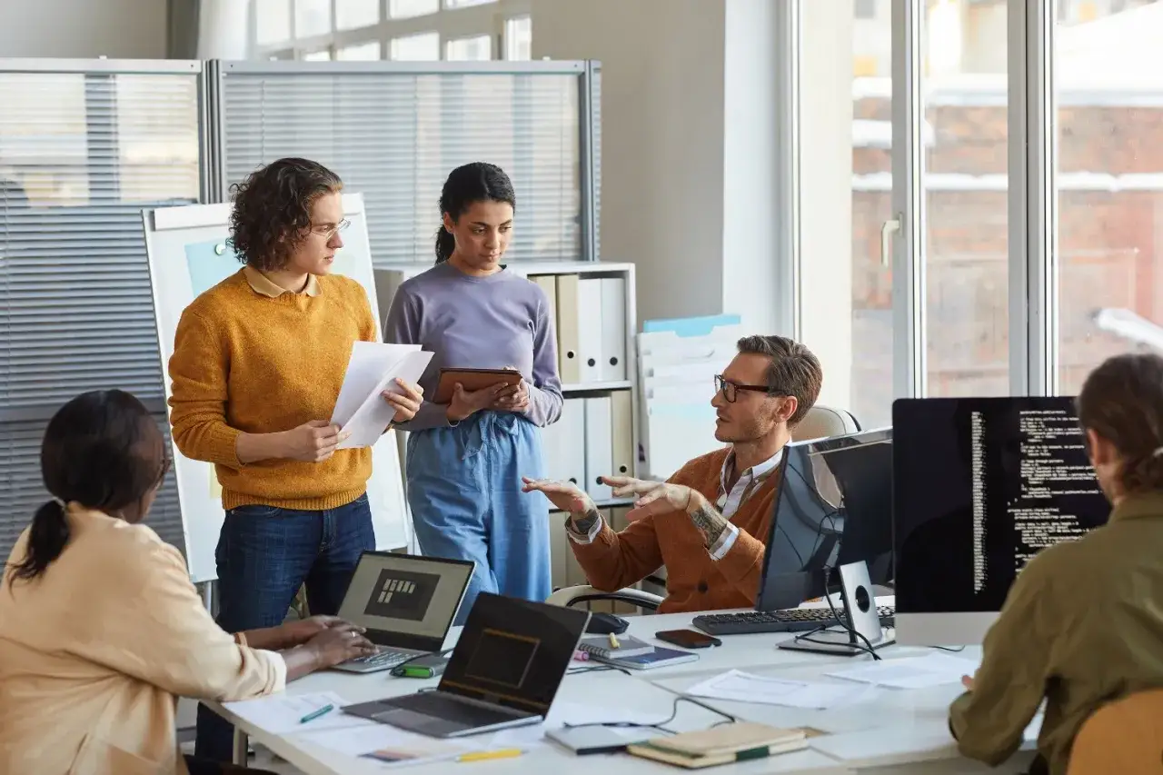 Ein Softwareentwickler erklärt seinem Team bei einem Meeting, wie der Code funktioniert.